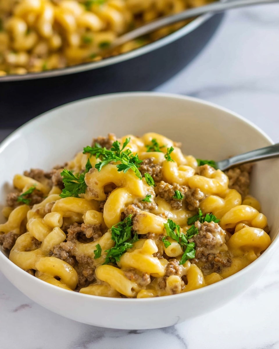 A close-up view of a black pan filled with cooked elbow macaroni pasta mixed thoroughly with browned ground beef. The macaroni is bright yellow with a smooth, slightly glossy texture, and the ground beef pieces are small, crumbly with a rich brown color. There is a wooden spoon partially seen stirring the mixture from the top left corner. The pan sits on a white marbled surface. photo taken with an iphone --ar 4:5 --v 7