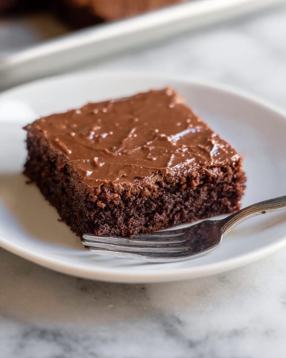 A metal baking tray filled with several square cuts of rich, brown brownies. One brownie is being lifted by a utensil with a white handle, showing its moist, slightly crumbly texture and shiny cracked top layer. The surface of each brownie is smooth with some cracks and a slightly glossy finish. The tray rests on a white marbled surface. photo taken with an iphone --ar 4:5 --v 7