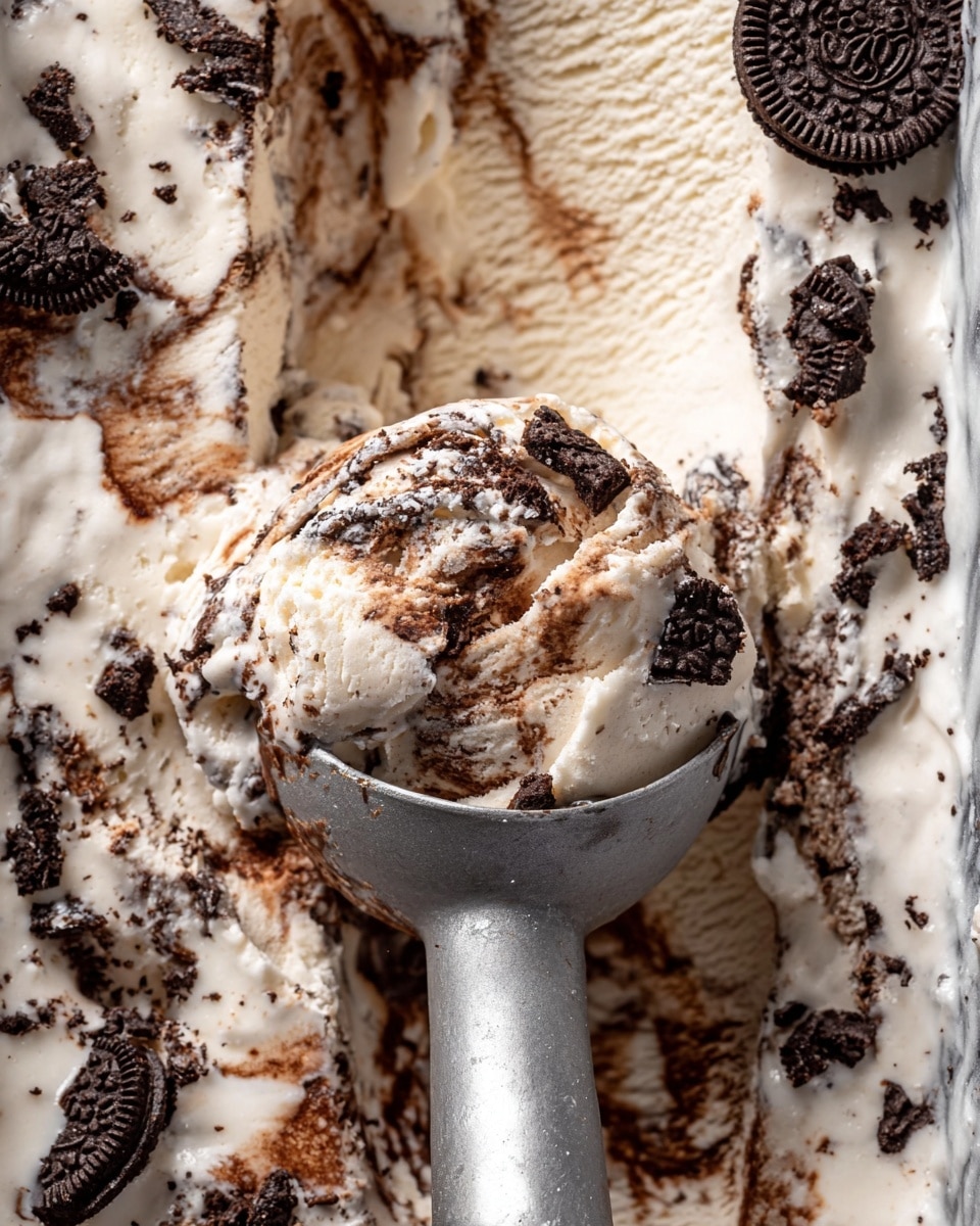 The image shows a close-up of cookies and cream ice cream being scooped with a metal ice cream scoop. The ice cream has a creamy white base mixed with swirls of rich brown chocolate and chunks of dark chocolate cookies. Pieces of cookie are scattered on top and embedded throughout the ice cream, creating a textured, layered effect. The scoop reveals a mix of creamy, smooth, and chunky textures with the chocolate swirls and cookie bits visible in the middle. The background is a white marbled texture. Photo taken with an iphone --ar 4:5 --v 7