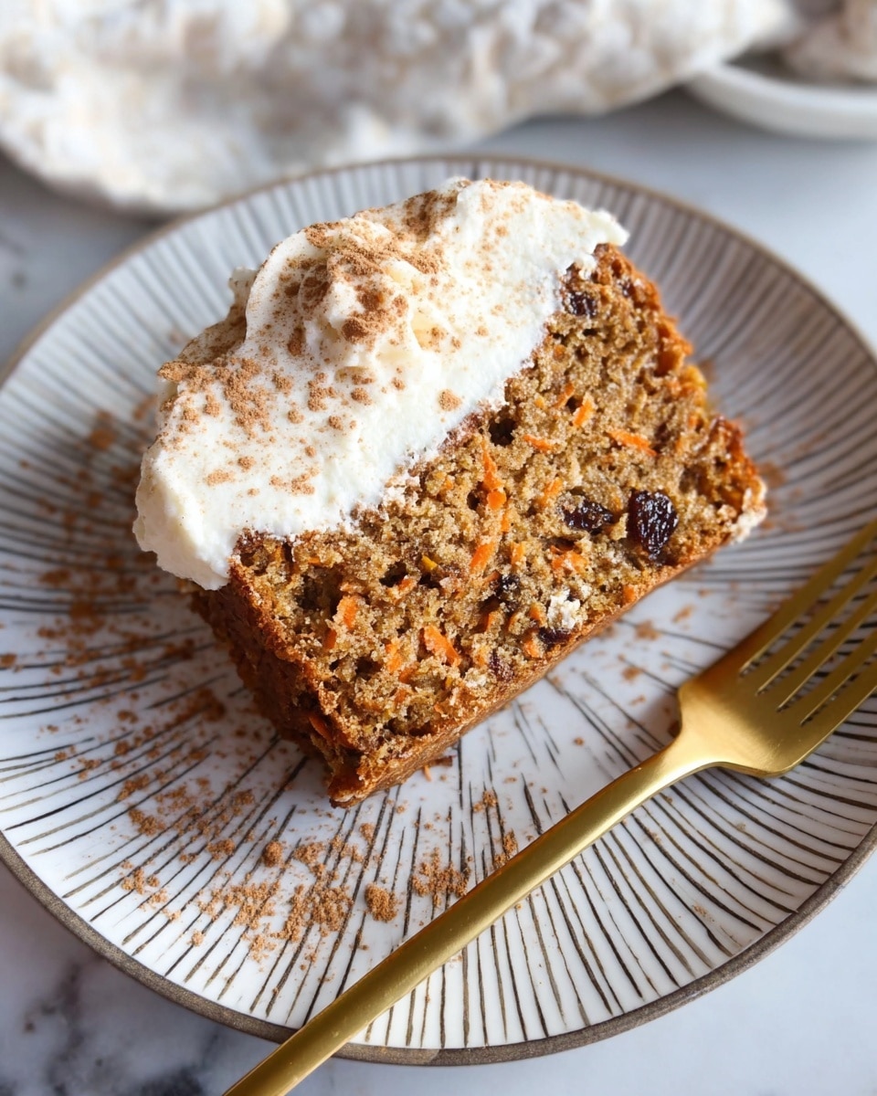 A slice of carrot cake with visible bits of shredded carrot and dark raisin pieces, showing a moist, crumbly texture with a light brown color. On top, there is a thick dollop of white cream, dusted with light brown cinnamon powder. The slice sits on a white plate with thin dark lines radiating from the center and some scattered cinnamon powder. Next to the cake is a gold fork. The background shows a white marbled texture with a cloth partially visible. Photo taken with an iphone --ar 4:5 --v 7