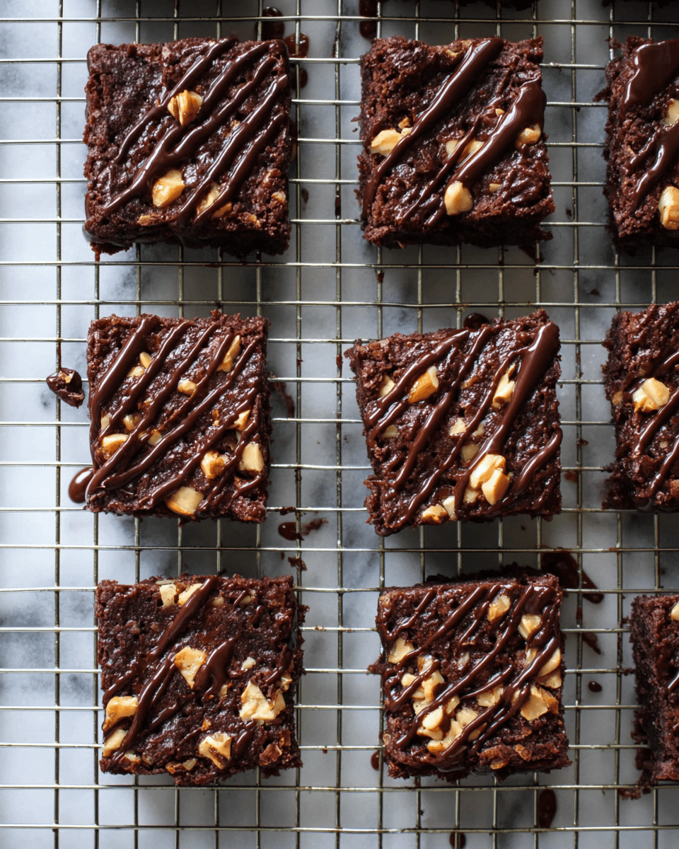 A stack of four rich, dark brown chocolate brownies with visible bits of nuts inside each piece, each layer thick and moist with a soft crumb texture. The brownies are drizzled with glossy dark chocolate sauce that drips slightly down the sides, adding a shiny contrast to the matte brownie surface. They stand tall on a flat surface with scattered nut pieces around, set against a white marbled texture background. A white bowl with a golden spoon is partially visible on the left side. Photo taken with an iphone --ar 4:5 --v 7