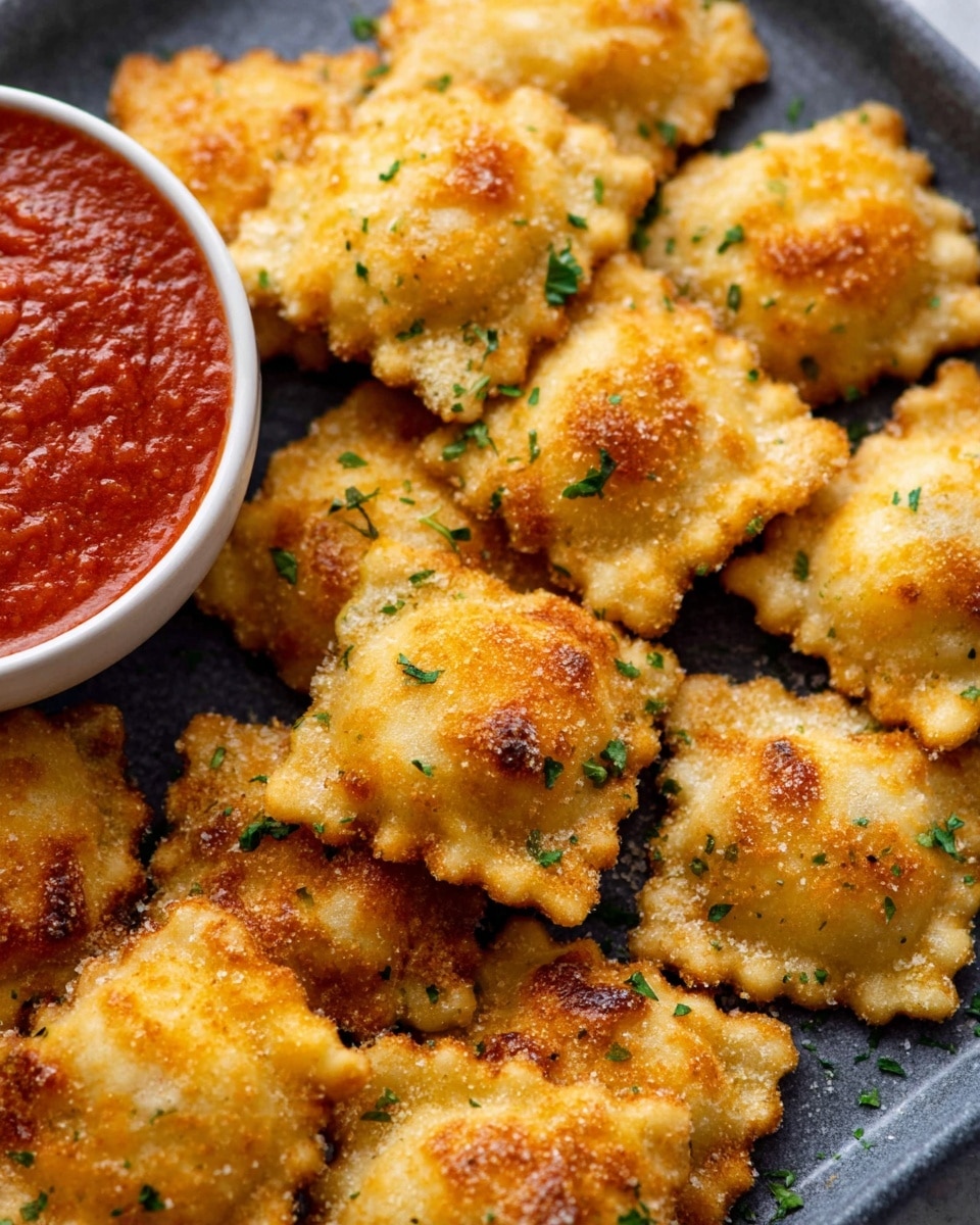 A close-up view of about fifteen golden brown, fried ravioli pieces scattered on a dark gray tray with a white marbled background. Each ravioli is square with crimped edges, showing a crispy, bubbly texture on the surface, with some browned and slightly darker spots. Small green parsley flakes are sprinkled over the ravioli, adding a touch of color. At the bottom left corner of the image, there is a white bowl filled with bright red marinara sauce. The photo has a warm, inviting look. photo taken with an iphone --ar 4:5 --v 7