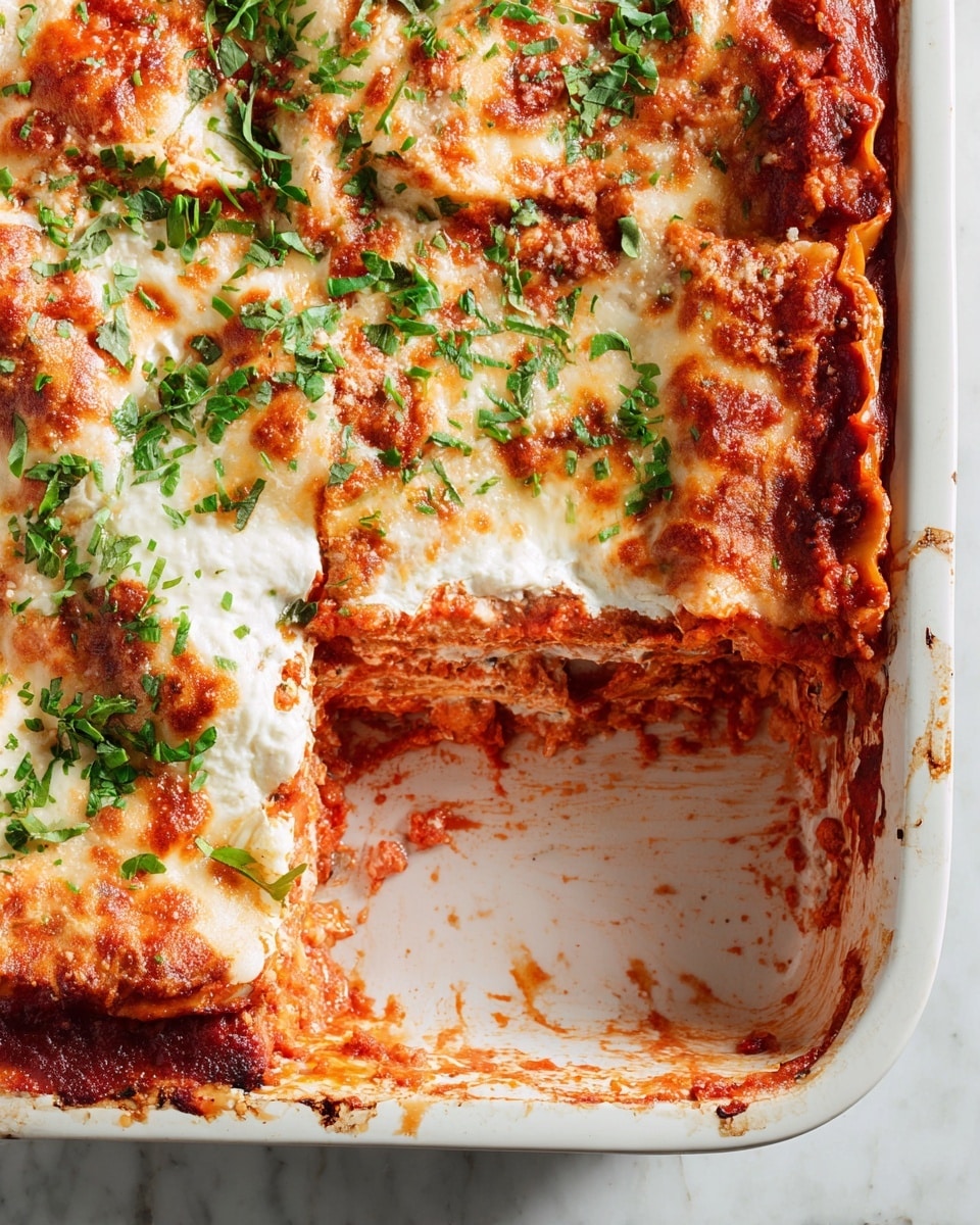 A white rectangular baking dish filled with a baked lasagna that has visible layers: the bottom layer is thick red tomato sauce mixed with ground meat, followed by wide, soft pasta sheets layered with creamy, melted cheese. The top layer is golden brown, bubbly melted cheese with some browned edges and sprinkled with fresh green chopped herbs and grated white cheese. A woman's hand is seen sprinkling the fresh herb on top. The baking dish sits on a wooden table with a red and white checkered cloth nearby, and the background is a white marbled texture. photo taken with an iphone --ar 4:5 --v 7