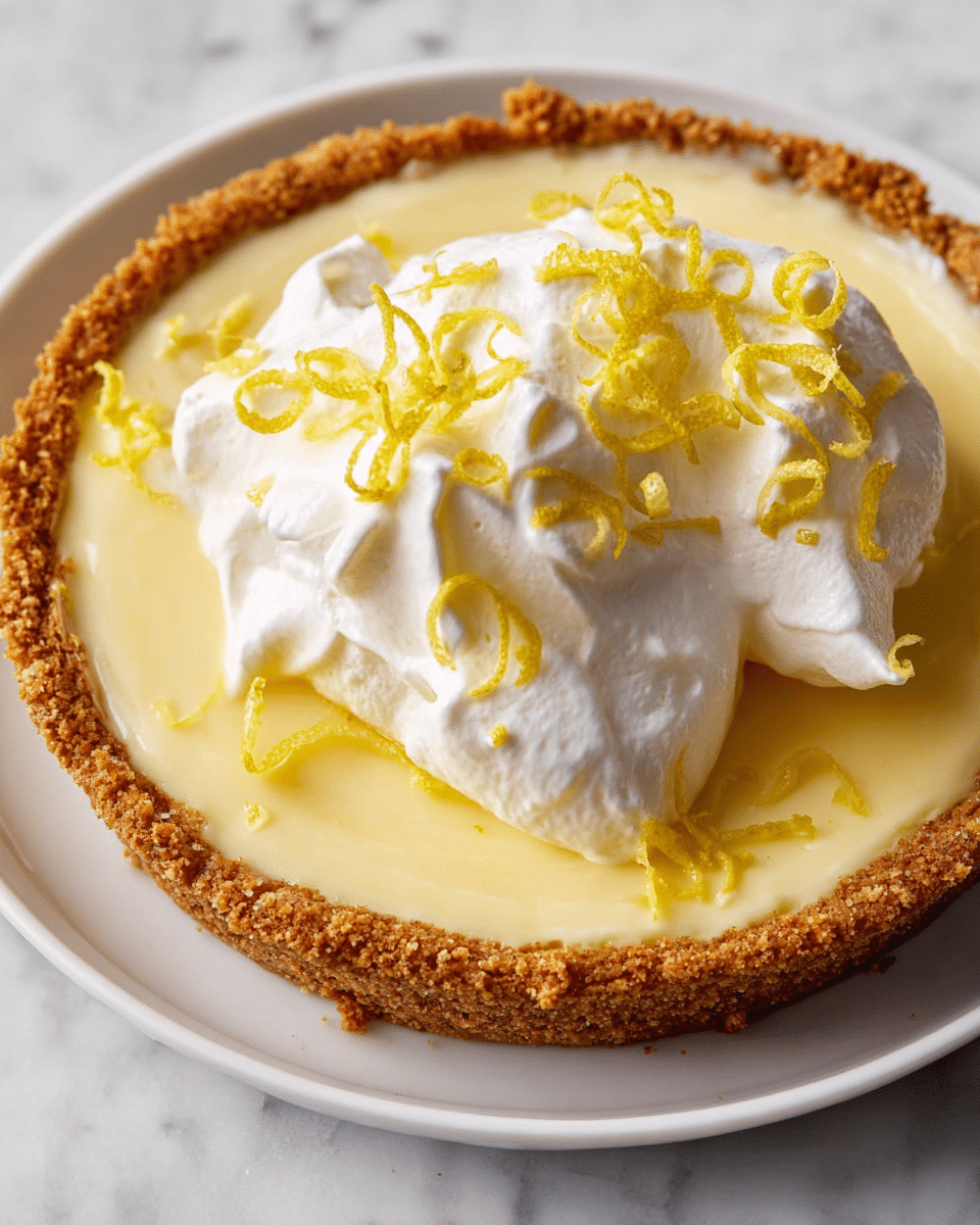 A single-layer lemon pie with a thick, smooth yellow filling sits on a white plate, surrounded by a golden brown, crumbly crust that rises slightly above the filling. On top, there is a large dollop of white whipped cream with soft peaks, scattered with thin, curly yellow lemon zest pieces. The pie is placed on a white marbled surface, showing a close-up overhead view. photo taken with an iphone --ar 4:5 --v 7
