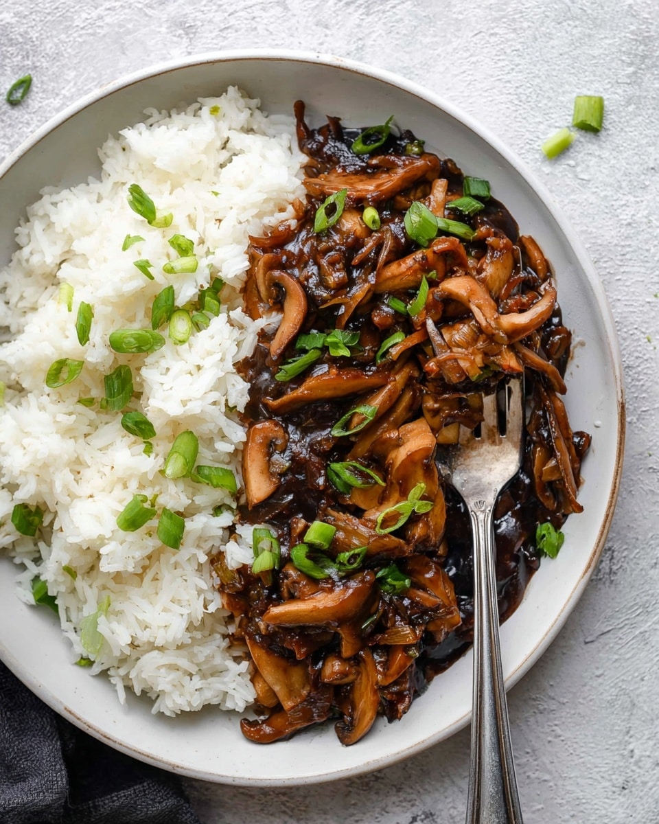 A white marbled textured background holds a medium white plate divided into two parts: one side has a fluffy layer of white rice with distinct grains, and the other side displays a thick layer of dark brown, glossy mushroom teriyaki sauce with tender cooked mushrooms spread unevenly; scattered on top are chopped green onion pieces adding bright green color contrast, and a silver fork rests on the plate with its tines partly placed on the rice layer photo taken with an iphone --ar 4:5 --v 7