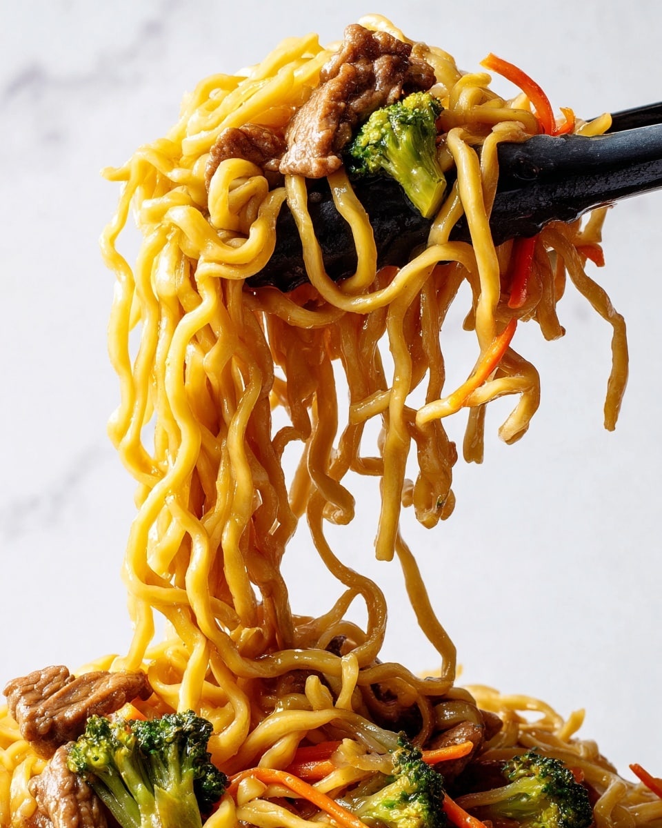 A close-up view of cooked yellow noodles lifted by black tongs, showing thick strands hanging down. Among the noodles are chunks of brown cooked meat, green broccoli florets, and thin strips of orange carrots, all mixed in the noodles. The sauce coating the noodles adds a shiny, slightly oily surface, making the texture look soft and juicy. The background is a white marbled texture, and the focus is on the details of the noodles and vegetables. Photo taken with an iphone --ar 4:5 --v 7