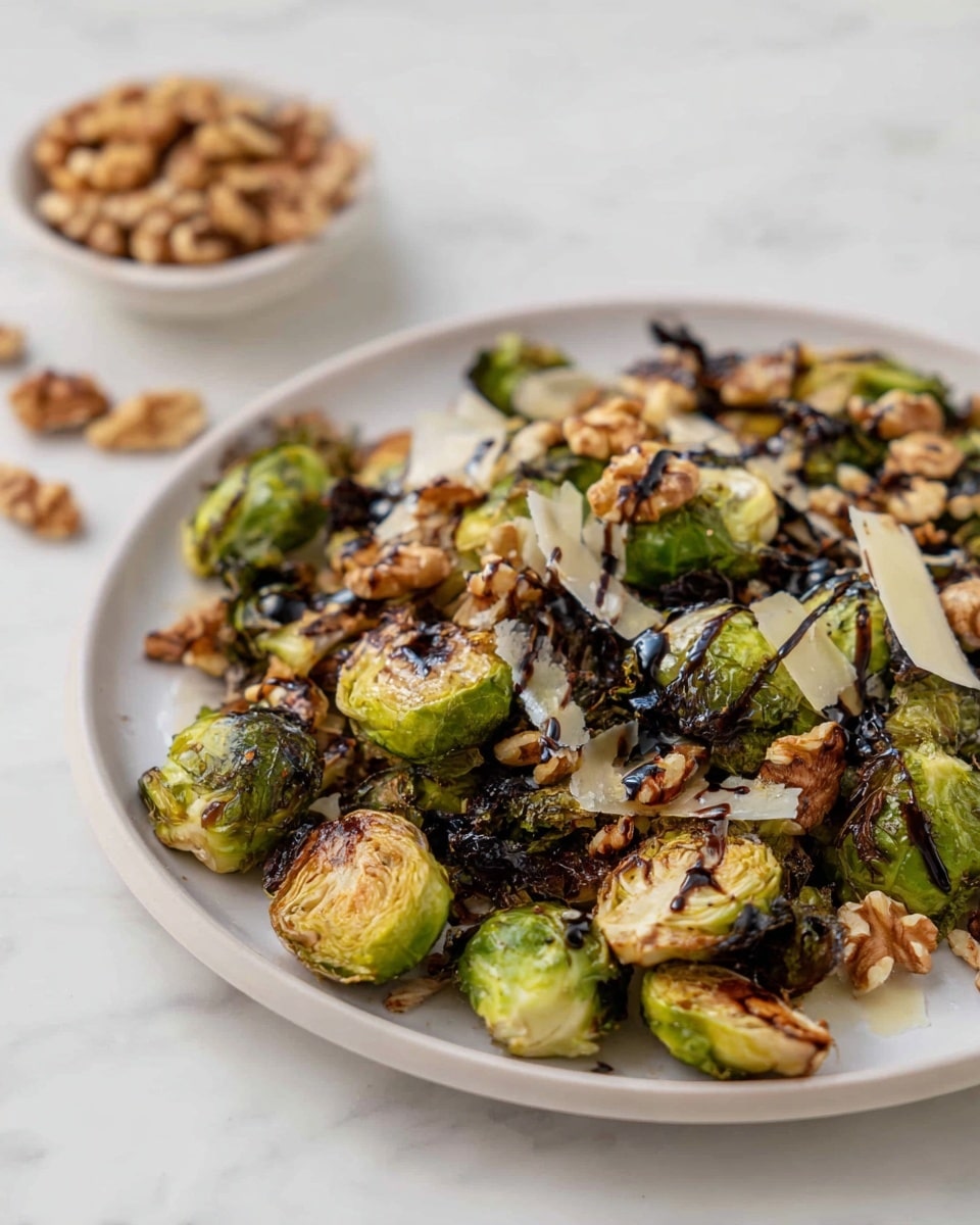 A white plate full of roasted Brussels sprouts cut into small pieces with browned, crispy edges forms the base layer. Scattered on top are uneven pieces of golden brown walnuts, adding a crunchy texture. Dark, glossy balsamic glaze is drizzled all over, creating a contrast against the green and brown of the sprouts. Thin shavings of pale cheese are spread randomly, melting slightly into the warm Brussels sprouts. On the plate's right side, a vintage silver spoon is partially resting on the food. Around the plate, pieces of walnuts are casually placed, with a small bowl filled with more walnuts at the top left. The setting features a white marbled surface with a beige cloth in the upper right corner. A silver fork lies at the bottom right of the image photo taken with an iphone --ar 4:5 --v 7
