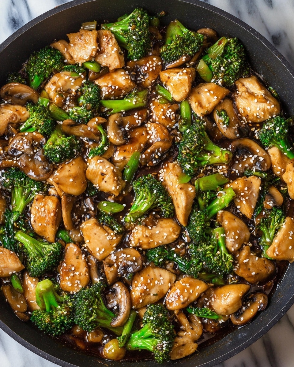 The image shows a close-up of a black pan filled with a stir-fry dish that has three main layers: light brown cooked chicken pieces, bright green broccoli florets, and sliced light brown mushrooms. The dish is coated in a dark, shiny sauce, scattered with small white sesame seeds across the top. The pan sits on a white marbled surface, and the colors of the ingredients stand out clearly. Photo taken with an iphone --ar 4:5 --v 7