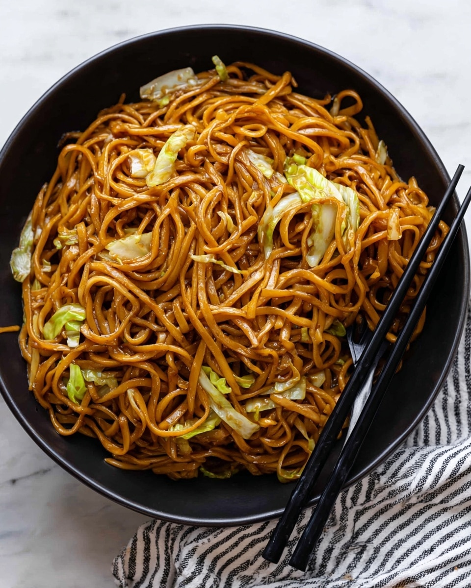 A black bowl filled with a large serving of stir-fried noodles tangled together with a glossy dark orange-brown sauce coating each strand. Scattered throughout are thin slices of light green cabbage and some translucent white cabbage pieces, adding texture and a splash of color to the dish. Two black chopsticks rest on the right side of the bowl, one picking up a small bundle of noodles. The bowl is placed on a white marbled surface next to a white and black striped cloth. photo taken with an iphone --ar 4:5 --v 7