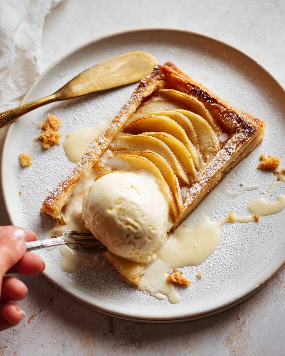 A white plate holds a rectangular slice of apple tart with a golden-brown flaky crust at the edges, topped with thinly sliced cooked apples arranged in neat rows. A scoop of melting vanilla ice cream rests on one side of the tart, with creamy melted ice cream pooling around it and the tart. Some powdered sugar is lightly dusted around the tart edges, and small pastry crumbs are scattered on the plate. A silver fork is cutting into the tart, with a woman's hand holding it. A gold and white knife lies near the ice cream. The plate sits on a white marbled textured surface. Photo taken with an iphone --ar 4:5 --v 7
