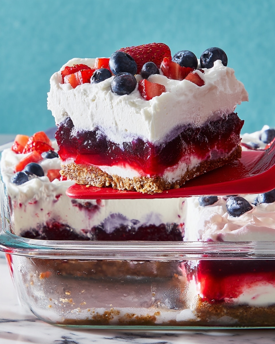 A slice of a layered berry dessert is lifted from a clear glass dish with a red spatula, showing five layers: a crumbly brown base, a dark purple berry jelly layer, a smooth white cream layer, a bright red mixed berry jelly layer, and a thick fluffy white whipped cream topping. The whipped cream is decorated with whole blueberries and chopped strawberries, adding pops of blue and red. The background is a white marbled texture with a soft blue backdrop, and the dish is partially visible with more whipped cream and berries inside. Photo taken with an iphone --ar 4:5 --v 7
