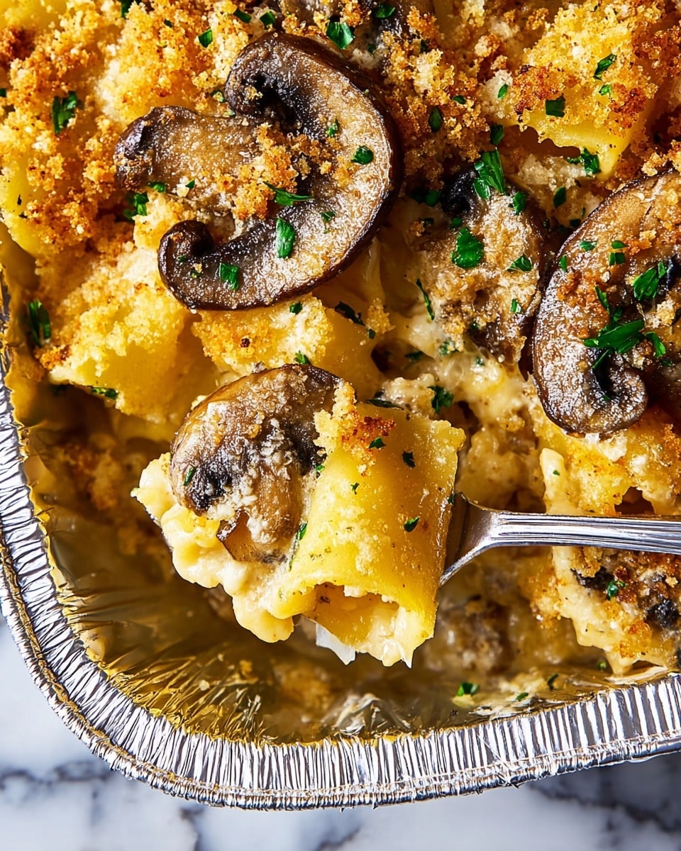 A close-up view of a baked pasta dish in a white foil container showing two layers: the bottom layer is yellowish roasted pasta tubes covered with melted cheese, and the top layer has golden-brown sautéed mushroom slices with a crumbly, crispy breadcrumb topping sprinkled with green herbs. A silver fork holds a bitten piece of pasta exposing the gooey cheese inside. The background surface is a white marbled texture. photo taken with an iphone --ar 4:5 --v 7