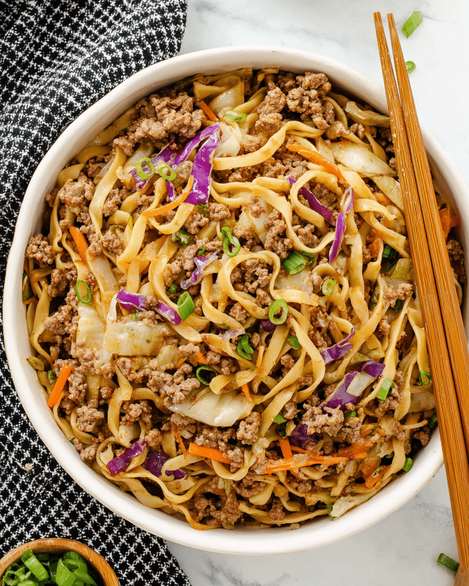 A bowl filled with a mix of flat, light brown noodles and cooked ground meat spread evenly throughout. There are several layers of thinly sliced white and purple cabbage pieces and small bits of orange carrot mixed in among the noodles and meat. Small sprinkle of chopped green onions are scattered on the top and throughout the dish. A pair of wooden chopsticks rests on the edge of the bowl which is white, and the bowl sits on a white marbled surface with a black and white checkered cloth to the side. Photo taken with an iphone --ar 4:5 --v 7
