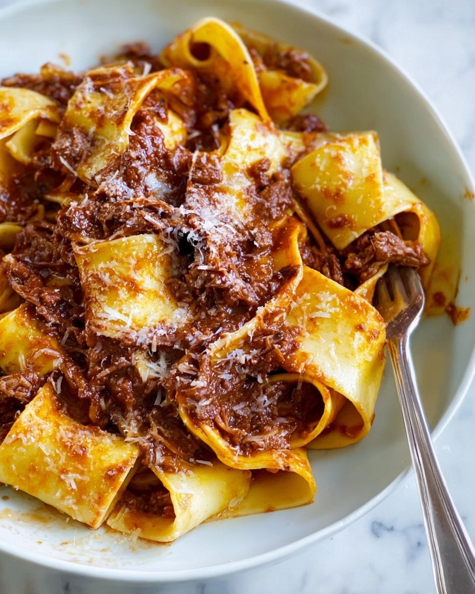 This image shows a close-up of wide pasta noodles layered thickly and loosely folded, covered with a rich, dark brown meat sauce that looks tender and chunky. The sauce is spread unevenly over the pale yellow pasta, with some areas showing a glossy oily shine and others sprinkled lightly with grated cheese. The dish is served in a white plate with a silver fork partially twisting a few noodles on the right side. The background is a white marbled texture. photo taken with an iphone --ar 4:5 --v 7