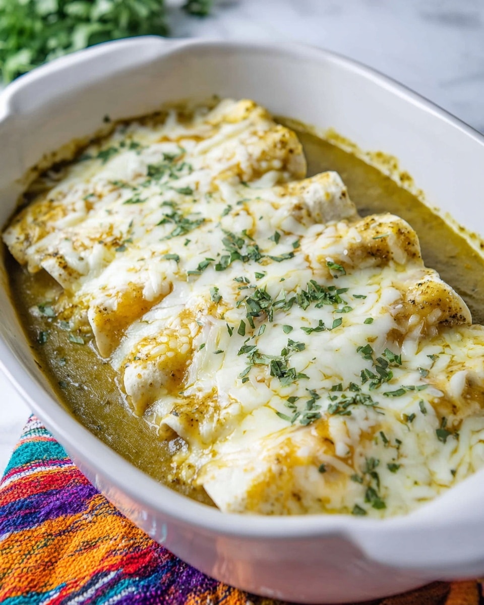 A white casserole dish filled with five rolled enchiladas placed side by side, each covered with melted white and light yellow cheese that looks soft and gooey. Underneath the enchiladas, there is a layer of green sauce that spills partly around the edges. The enchiladas are sprinkled with small chopped green herbs on top, adding color and freshness. The dish is set on a colorful woven cloth on a white marbled surface, with some blurred green leaves in the background. photo taken with an iphone --ar 4:5 --v 7