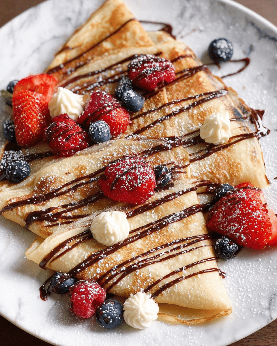 The image shows three folded golden-brown crepes arranged on a white plate, each crepe drizzled with thin lines of dark chocolate sauce. On top and around the crepes, there are small dollops of light cream and a mix of fresh berries including whole raspberries, halved strawberries, and blueberries dusted lightly with powdered sugar. The crepes have a soft, slightly crispy texture on the edges, and the berries add bright reds and blues contrasting with the pale cream and light brown crepes. The background is a white marbled surface. Photo taken with an iphone --ar 4:5 --v 7