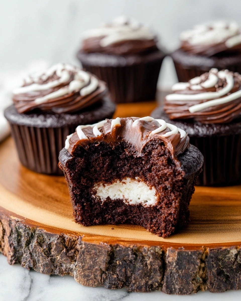 A close-up of four chocolate cupcakes sitting on a thick wooden stand with rough bark edges, placed on a white marbled surface. The front cupcake is cut open showing three layers: a dark brown moist cake base, a white creamy filling in the center, and a glossy dark chocolate frosting spread thickly on top. A swirl of white icing decorates the top of each cupcake. The other three cupcakes are whole and lined up blurred in the background, all showing the same dark chocolate frosting with white icing details. Photo taken with an iphone --ar 4:5 --v 7