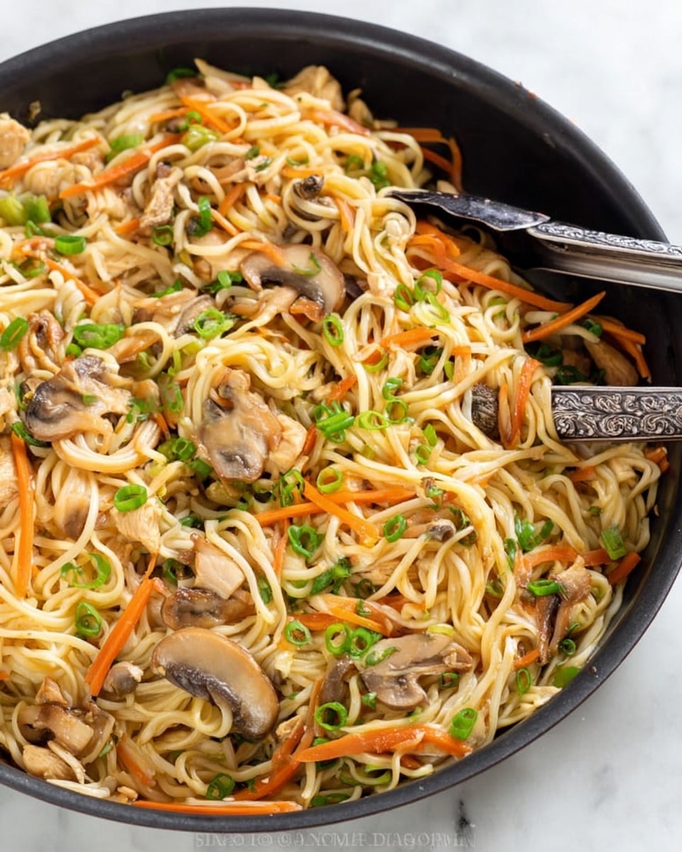 The image shows a black pan filled with stir-fried noodles mixed with sliced mushrooms, thin carrot strips, and small pieces of chicken. The noodles are light yellow and slightly shiny with a soft texture. The mushrooms are brown and tender-looking, scattered evenly throughout. The carrots add a bright orange color and a bit of crunch. Small green onion pieces sprinkled on top bring a fresh pop of green. Dark tongs rest inside the pan which sits on a white marbled surface. photo taken with an iphone --ar 4:5 --v 7