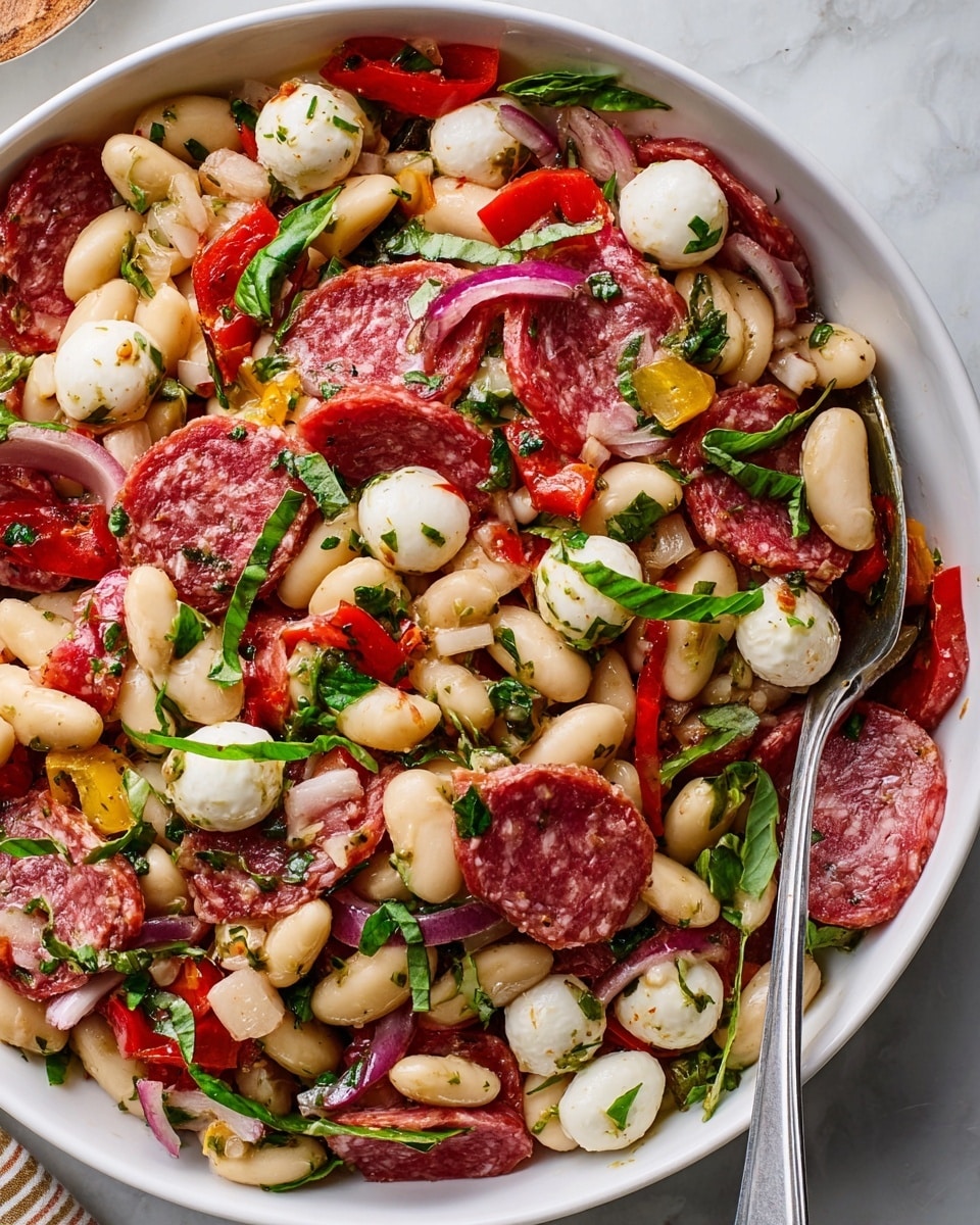 The image shows a white bowl filled with a colorful salad made of white beans, pieces of salami, white mozzarella chunks, chopped red onions, small red and yellow peppers, and fresh green basil leaves mixed throughout. There are two smaller white plates with the same salad on a white marbled surface, one of which has a fork resting on it with some beans, mozzarella, and salami on the fork. Next to the plates is a small white bowl filled with chopped green herbs. The textures show smooth beans, soft cheese, thin slices of salami, and fresh leafy herbs, creating a vibrant and fresh look. Photo taken with an iphone --ar 4:5 --v 7