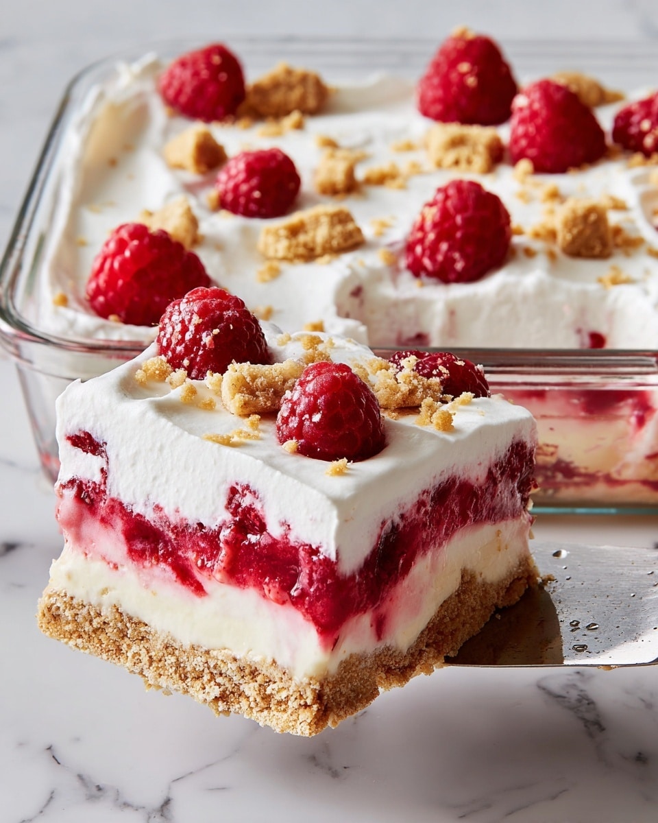 The dessert has four layers, starting with a crumbly light brown base at the bottom, followed by a smooth creamy white layer above it. Above the cream is a thick, bright red raspberry layer with visible whole raspberries and seeds. The top layer is fluffy white whipped cream with a soft texture, decorated with fresh raspberries and small pieces of light brown crumbs scattered across the surface. The dessert is in a clear square glass dish, set on a white marbled surface, and a piece is lifted with a metal spatula. Photo taken with an iphone --ar 4:5 --v 7