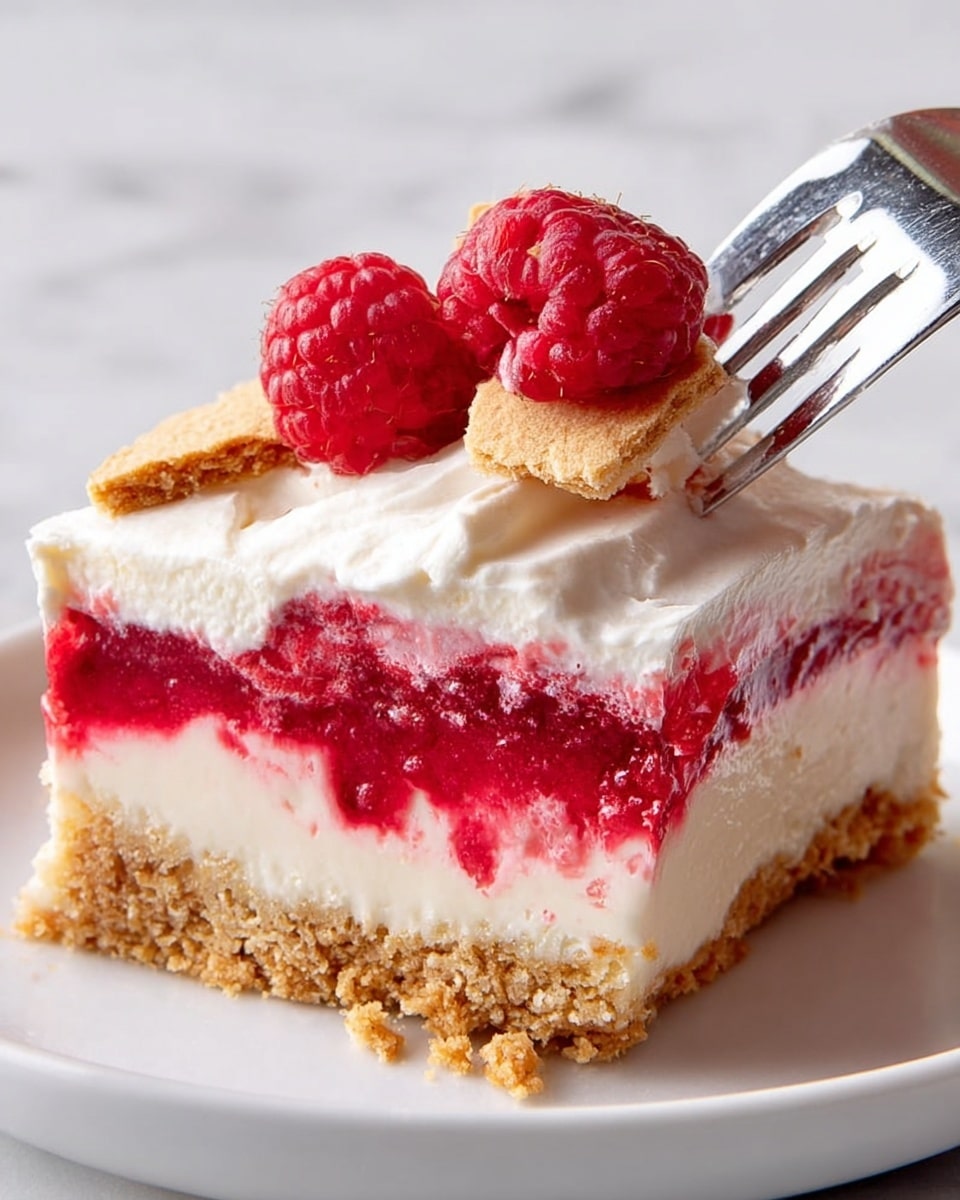 A close-up of a layered dessert slice on a white plate, placed on a white marbled texture. The bottom layer is a crumbly golden brown crust with a rough texture. Above it is a smooth, creamy white layer, topped by a bright red raspberry layer with visible fruit pieces. On top of the raspberry layer is a thick, soft white cream layer. Three fresh raspberries sit on top as decoration, along with two small broken pieces of a crunchy cookie. A fork is cutting into the dessert, lifting a piece showing the creamy white layer. Photo taken with an iphone --ar 4:5 --v 7