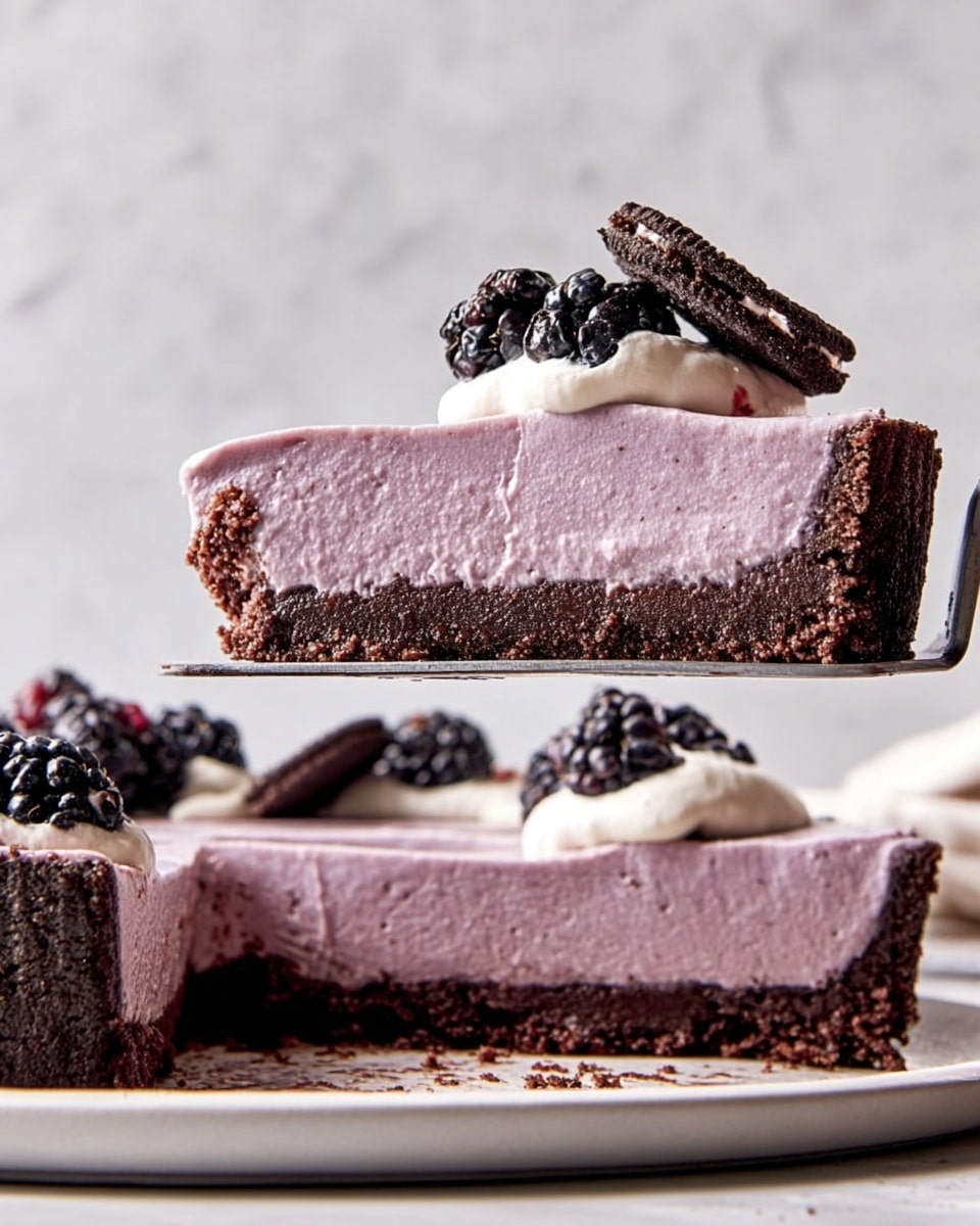 A slice of pie is shown held above the rest of the pie on a silver spatula. The pie has three layers: a dark brown crumbly crust at the bottom, a thick smooth light purple filling in the middle, and a small dollop of light cream on top. The cream has a slightly soft texture and is decorated with a cluster of shiny blackberries and a small dark chocolate cookie piece placed on top. The pie sits on a white plate, and the background is a white marbled texture. Photo taken with an iphone --ar 4:5 --v 7
