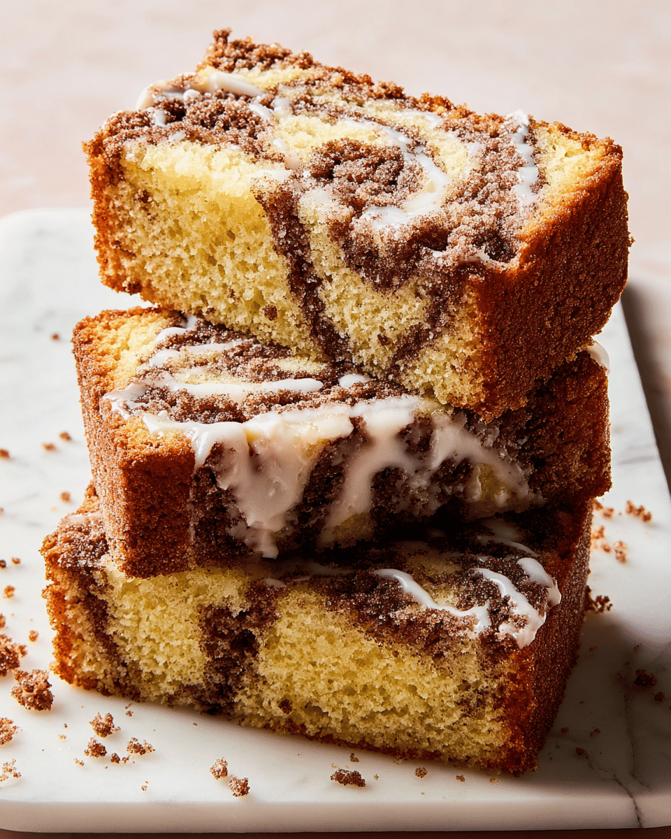 This image shows three slices of cinnamon swirl cake stacked on top of each other on a white rectangular plate placed on a white marbled textured surface. Each slice has two layers: a light golden yellow crumb with a soft texture mixed with dark brown cinnamon swirls throughout. The top layer of the slices is a darker brown, slightly rough and crumbly, with a light white glaze drizzled unevenly across. Crumbs are scattered around the slices on the plate and surface. Photo taken with an iphone --ar 4:5 --v 7
