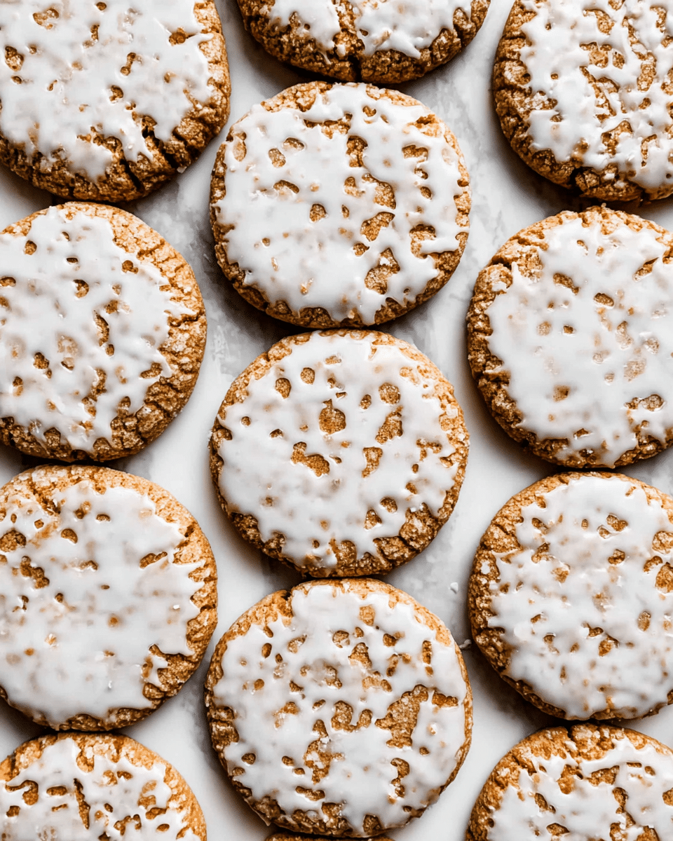 The image shows many round cookies placed closely together on a white marbled surface. Each cookie has a single layer with a golden brown base that looks slightly cracked and textured. On top, they are covered with uneven white icing that partially covers the surface, allowing some of the cookie's texture and color to show through in patches. The cookies are arranged neatly in rows, filling the frame. photo taken with an iphone --ar 4:5 --v 7