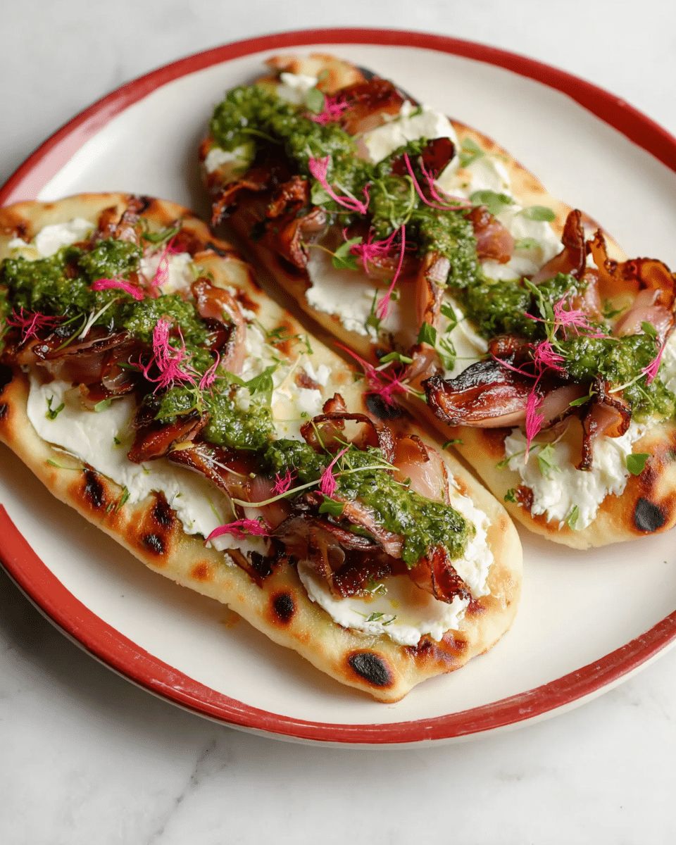 The image shows two open-faced flatbread slices placed side by side on a round white plate with a red rim, set on a white marbled surface. Each flatbread has four visible layers: the bottom layer is a slightly charred, golden-brown flatbread base; the second layer consists of a thick, creamy white cheese spread; the third layer is made up of folded, caramelized brown mushrooms or a similar ingredient with a rich, glossy texture; the top layer is a vibrant green sauce, likely pesto, spread along the center, garnished with small pink edible flower petals and delicate green herb sprigs. The dish looks fresh and colorful, with a mix of creamy, savory, and herbal elements. photo taken with an iphone --ar 4:5 --v 7