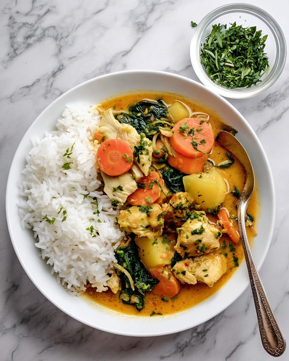 A white bowl holds a meal with two main layers: on the left, a fluffy white rice, and on the right, a colorful stew with multiple parts. The stew layer includes light brown chicken pieces, orange carrot slices, pale yellow potato chunks, and dark green spinach leaves, all mixed in an orange creamy sauce. On top, there are small green herb bits sprinkled. A silver spoon rests on the right side, partly in the stew. In the top right, a small clear bowl holds bright green chopped herbs. The setting is on a white marbled surface. photo taken with an iphone --ar 4:5 --v 7