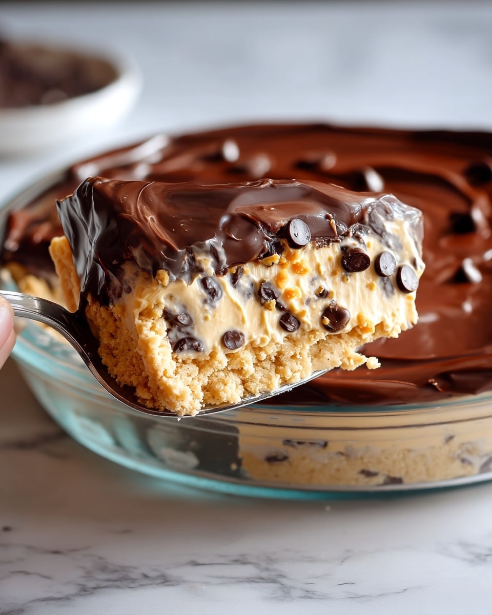 A slice of three-layer dessert is being lifted from a clear glass pie dish set on a white marbled surface. The bottom layer is crumbly and light beige, resembling a cookie crust. The middle layer is a creamy, pale tan filling mixed with dark chocolate chips scattered throughout. The top layer is a thick, glossy dark chocolate glaze with a smooth texture and slight ripples. The edges of the chocolate layer drip slightly over the creamy middle layer. The spoon holding the slice is silver, reflecting some light. Photo taken with an iphone --ar 4:5 --v 7