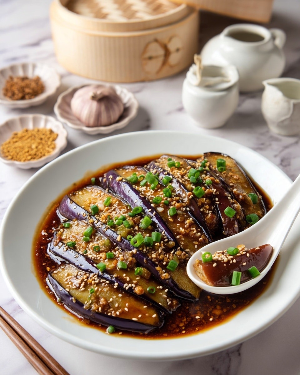 A white round plate holds sliced cooked eggplant pieces arranged in one layer, with a glossy dark purple skin visible on the outside and soft pale interior. The eggplants are covered with a shiny brown sauce, scattered with small beige sesame seeds and chopped green onions adding texture and color contrast. A white spoon rests on the edge of the plate, scooping some eggplant and sauce. The plate is set on a white marbled surface with a bamboo steamer, garlic bulb in a small white dish, sliced ginger root, and another white dish with mustard seeds arranged softly in the background. Photo taken with an iphone --ar 4:5 --v 7